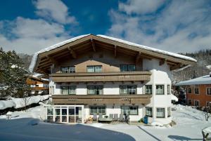 a large house with a snow covered roof at Appartements Familie Grundner in Leogang