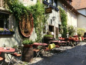 an outdoor patio with tables and chairs and plants at Altfraenkische Weinstube in Rothenburg ob der Tauber