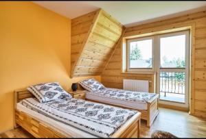 two beds in a room with a window at By the River in Chochołów