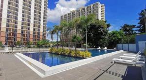 a large swimming pool with two tall buildings at Snuggle in Bed near Mactan Airport in Lo-oc