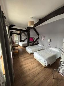two beds in a room with wooden floors and beams at Hotel Le Bon Laboureur in La Charité-sur-Loire +46 photos