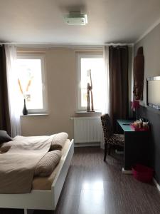 a bedroom with a bed and a desk and two windows at Hotel Sandmanns am Dom in Cologne