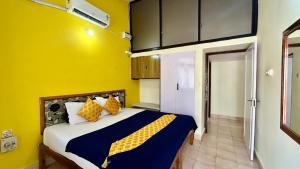 ein Schlafzimmer mit einem Bett und einer gelben Wand in der Unterkunft Muffys Service Apartment in Baga