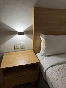 a bedroom with a bed and a nightstand with a light at Hotel Posada Real in Lagos de Moreno
