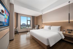 a bedroom with a large white bed and a large window at Shenzhen Meiji Hotel in Shenzhen