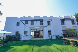 Un edificio blanco con un patio con sillas y mesas. en Villa Rosa Cotonou, en Cotonou
