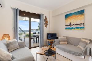 a living room with two couches and a balcony at Almyrida Bay View House V BY APOKORONAS-VILLAS in Almirida