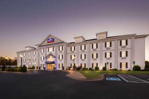 a large white building with a parking lot at Howard Johnson by Wyndham Jackson in Jackson