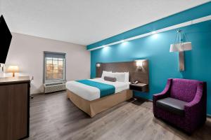 a hotel room with a bed and a chair at Howard Johnson by Wyndham Jackson in Jackson