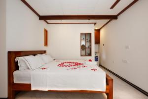 a bedroom with a white bed with red flowers on it at Paradise Sunrise Villa in Ahungalla