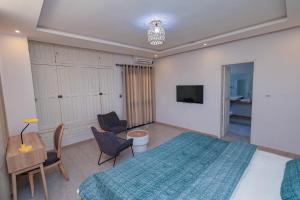 Un dormitorio con una cama, un escritorio y un televisor. en Villa Rosa Cotonou, en Cotonou