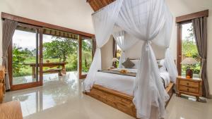 a bedroom with a canopy bed and large windows at Tenggala Villa Ubud by Mahaputra in Ubud +23 photos