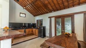 a kitchen with a wooden table and a black refrigerator at Tenggala Villa Ubud by Mahaputra in Ubud
