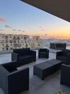 um quarto com sofás e um ecrã de projecção no telhado em Skyline Soak, Views & Jacuzzi em St Julian's