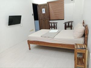 a bedroom with a bed with a tv and chairs at WJV Inn Baltan Extension in Puerto Princesa City