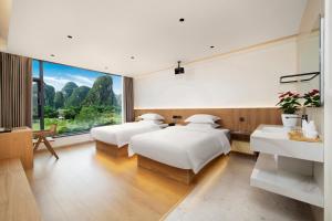 two beds in a room with a large window at Yangshuo Hidden Dragon Villa in Yangshuo