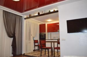 cocina con armarios rojos, mesa y sillas en Apartment On Pribuzhskaya 2, en Khmelʼnytsʼkyy