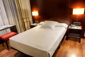 a bedroom with a large white bed and a desk at Zenit Valencia in Valencia