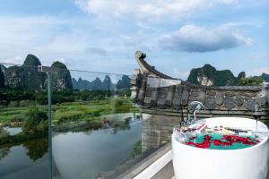 a bath tub with a view of a river and mountains at Yangshuo Hidden Dragon Villa in Yangshuo