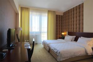 ein Hotelzimmer mit einem Bett, einem Schreibtisch und einem TV in der Unterkunft Hotel Turist in Kraljevo