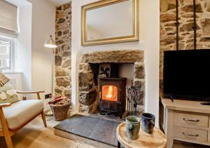 a living room with a stone fireplace and a tv at Ty Fin Cottage with Hot Tub in Llanbedrog