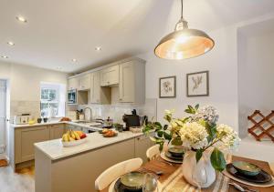 a kitchen with a table with a bowl of fruit on it at Ty Fin Cottage with Hot Tub in Llanbedrog