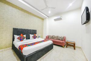 a bedroom with a large bed and a red couch at FabHotel Kavya Inn - Nr The Mall of Faridabad in Faridabad