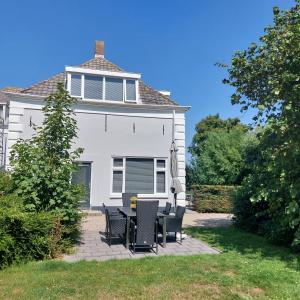 a white house with a table and chairs in the yard at Hof Christina Vakantiewoningen in Vrouwenpolder