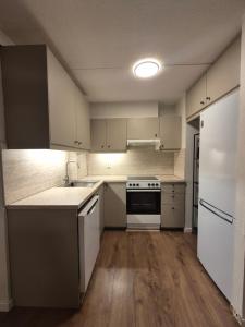 an empty kitchen with white appliances and wooden floors at Moderne 2 Roms Leilighet i Hjertet av Oslo in Oslo +6 photos