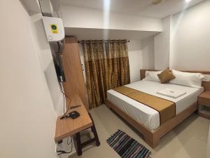 a small bedroom with a bed and a television at CLASSIC COMFORT Lodge in Mangalore