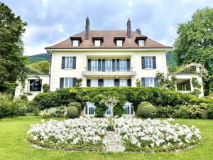 a large house with a flower garden in front of it at Chateau d 'Echenevex, Geneva in Échenevex