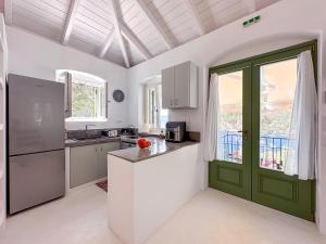 a kitchen with white cabinets and a green door at Panta'kei in Stavros