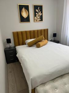 a white bed with a wooden headboard and white sheets at Komarom Luxe Apartment in Komárom