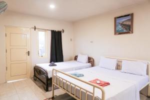 a room with two beds and a door at Komodo Shores Homestay in Labuan Bajo