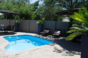 a swimming pool with chairs and a fence at A Contempo Guesthouse in Bloemfontein