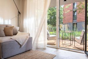 een woonkamer met een bank en een glazen schuifdeur bij Hill Apartment in Palanga