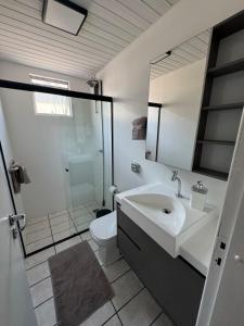 a bathroom with a sink and a toilet and a mirror at Apartamento 2 quartos com ar-condicionado, sacada com churrasqueira no centro in Balneário Camboriú +10 photos