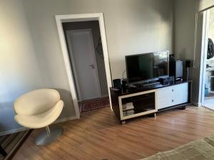 a living room with a television and a chair at Apartamento 2 quartos com ar-condicionado, sacada com churrasqueira no centro in Balneário Camboriú