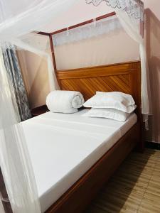 a bed with white sheets and pillows on it at Sunset Inn Lodge in Arusha