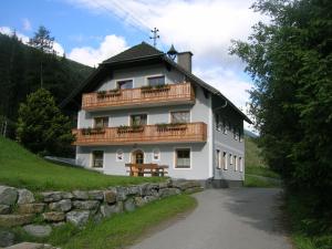 ein großes weißes Gebäude mit Balkon auf einem Hügel in der Unterkunft Ferienwohnung Aignerhof in Schellgaden