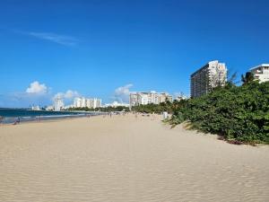 a beach with people walking on the sand and buildings at Latitude Adjustment in San Juan