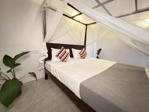 una camera da letto con un letto con lenzuola e cuscini bianchi di Sunliya Resort a Tangalle