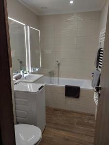 a bathroom with a tub and a sink and a toilet at Gold Residence Apartman in Hajdúszoboszló +20 photos