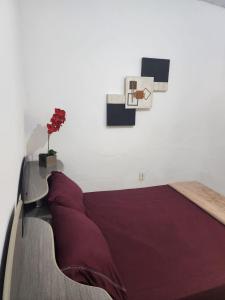ein Schlafzimmer mit einem Bett mit lila Kissen an einer Wand in der Unterkunft Casa no coração de Maricá in Maricá
