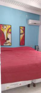 1 dormitorio con 1 cama roja y 2 cuadros en la pared en Bosque del Este II, en Balneario Buenos Aires