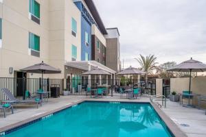 a pool at a hotel with chairs and tables and umbrellas at TownePlace Suites by Marriott Merced in Merced