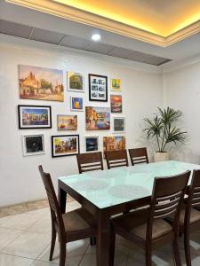 ein Esszimmer mit einem Tisch, Stühlen und Bildern an der Wand in der Unterkunft Villa De Ciudad in Lapu Lapu City