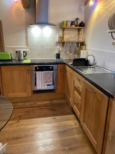 a kitchen with wooden cabinets and a stove top oven at The Cow House in Shap