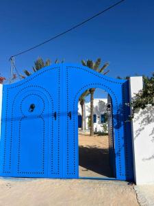 a blue gate with an open door at Menzel à Midoun in Al Maqārisah