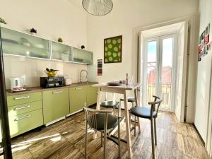eine Küche mit grünen Schränken sowie einem Tisch und Stühlen in der Unterkunft iMinerva Garden Panoramic Suite in Salerno